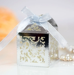 Macro shot of silver laser-cut floral candy box with light blue satin ribbon bow