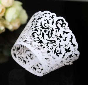 Detail of white laser-cut cupcake wrappers with vine lace patterns and wavy edges