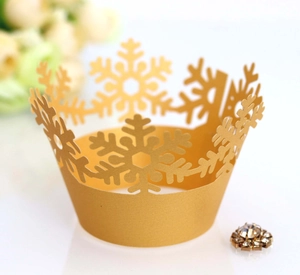 Macro shot of gold snowflake laser-cut lace cupcake wrapper with shimmering finish