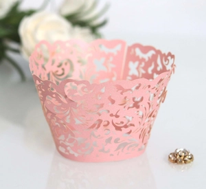 Detail of pink laser-cut lace cupcake wrappers with elegant floral vine patterns