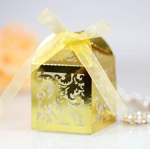 Detail of laser-cut golden wedding favor box with ornate hollow patterns and silk ribbon