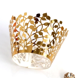 Macro detail of laser-cut gold cupcake wrapper with elegant leaf and vine pattern