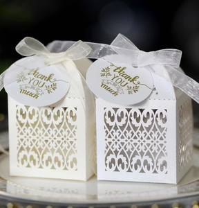 Close-up of laser cut wedding favor boxes with organza ribbons and thank you tags