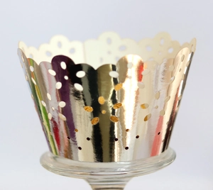 Close-up of laser-cut cupcake wrappers with golden floral patterns and wavy edges