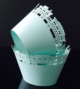 Detail of laser-cut light blue cupcake wrappers featuring an intricate train design