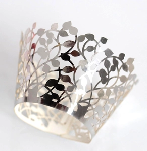 Macro shot of silver laser-cut cupcake wrappers with elegant hollowed leaf pattern details