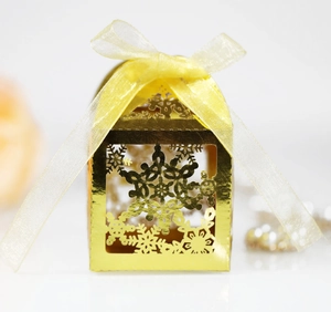 Detail of laser-cut gold snowflake candy box with elegant yellow ribbon bow decoration