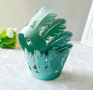 Detailed laser-cut feather pattern on a cyan paper cupcake wrapper for wedding decor