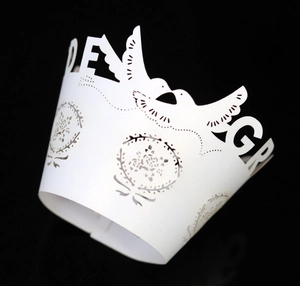 Detail of white laser-cut cupcake wrapper featuring love doves and floral wreath design