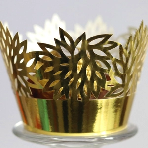 Elegant gold laser-cut cupcake wrappers with intricate leaf patterns for weddings