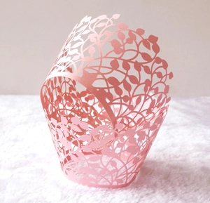 Detailed laser-cut leaf pattern on light pink cupcake wrapper with subtle shimmer