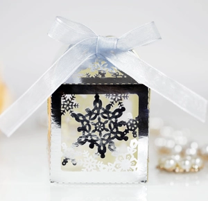 Close-up of a silver mirror snowflake laser-cut gift box with a light blue satin ribbon bow