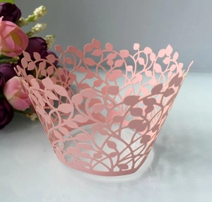 Close-up of pink laser-cut cupcake wrapper with intricate leaf and vine filigree design