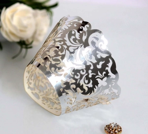 Close-up of silver laser-cut cupcake wrappers with intricate floral patterns for weddings
