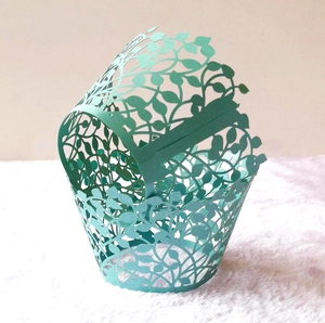 Detail of mint green laser-cut cupcake wrapper with elegant hollowed leaf pattern