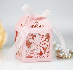 Detailed close-up of pink laser-cut hollow gift box with snowflake pattern and silk ribbon