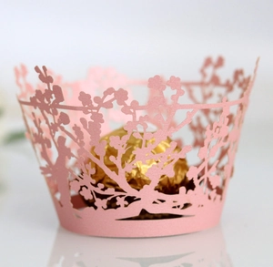 Detailed laser-cut cupcake wrapper featuring pink floral and tree pattern on white background