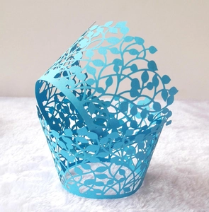 Close-up of sky blue laser-cut cupcake wrappers with intricate leaf and vine patterns