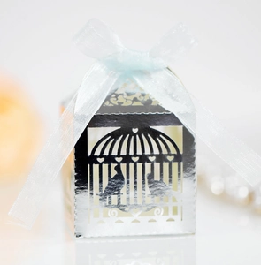 Detail of silver laser-cut wedding favor box with bird cage design and blue ribbon