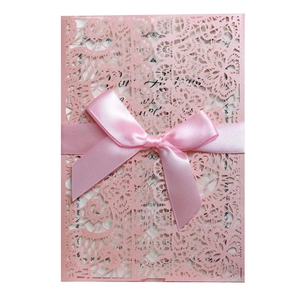 Detail of pink laser-cut lace wedding invitation with a satin ribbon and printed insert