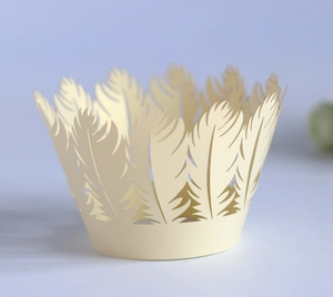 Detailed laser-cut feather pattern on cream-colored cupcake wrapper for wedding decor