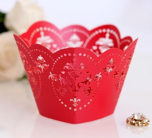 Close-up of red laser-cut cupcake wrappers with intricate vintage patterns for wedding decor