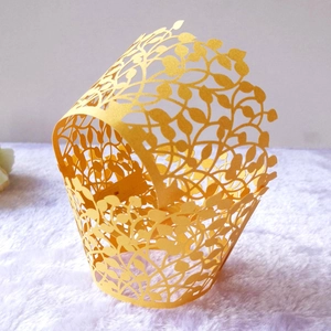 Detailed laser-cut vine and leaf patterns on a yellow cupcake wrapper with tab closure