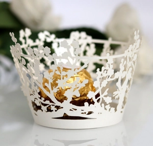 Close-up of laser-cut white cupcake wrapper with intricate branch and floral patterns