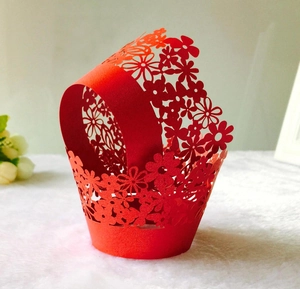 Macro shot of laser-cut red floral cupcake wrapper on white soft background
