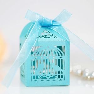 Close-up of laser-cut birdcage favor box in sky blue with ribbon and hollow heart detail