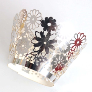 Detail of laser-cut silver cupcake wrapper with elegant floral and daisy patterns