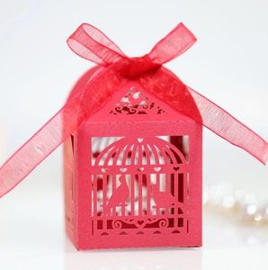 Macro detail of red laser-cut birdcage candy box with elegant organza ribbon bow