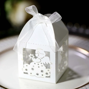 Detail of white laser-cut angel gift box with organza ribbon on a ceramic tray