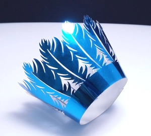 Detailed laser-cut feather pattern on metallic blue cupcake wrapper with reflective finish
