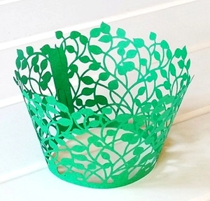 Detail of green laser-cut cupcake wrapper featuring a delicate leaf and vine pattern