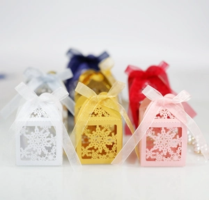 Close-up of laser-cut snowflake hollow gift boxes with satin ribbons in various colors