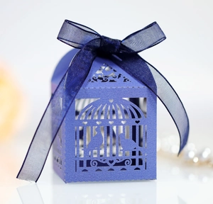 Macro detail of laser-cut birdcage candy box with purple ribbon for wedding gifts
