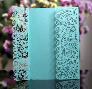 Detail of laser-cut floral lace pattern on teal pearlescent wedding invitation card