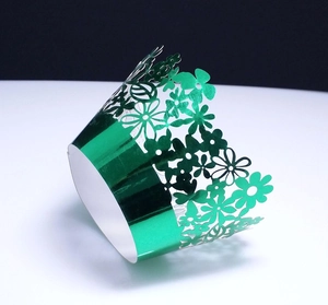 Detail of laser-cut floral green metallic paper cupcake wrappers for party decoration