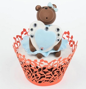 Detail of orange laser-cut cupcake wrapper and brown bear cake topper with blue heart