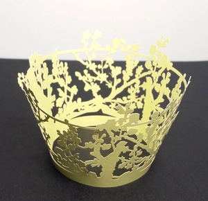 Detailed laser-cut tree pattern on pale yellow cupcake wrapper for party decoration