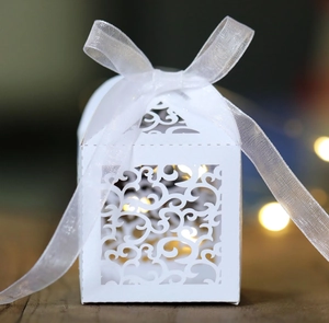 Elegant laser-cut wedding favor box in white with scroll patterns and chiffon ribbon