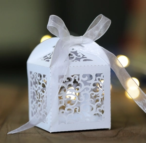Macro detail of laser-cut wedding candy box with white organza ribbon and scroll patterns