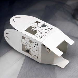 Macro detail of laser-cut white favor box showing angel and star hollow design