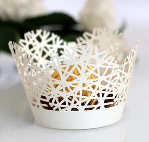 Macro view of white laser-cut cupcake wrapper with delicate snowflake branch patterns