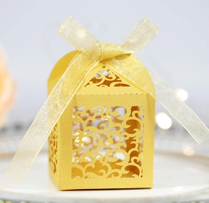 Detail of laser-cut wedding candy box with hollow floral pattern and yellow ribbon