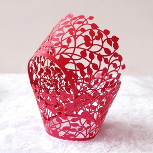 Red laser-cut hollow leaf vine cupcake wrappers on white plush surface for weddings