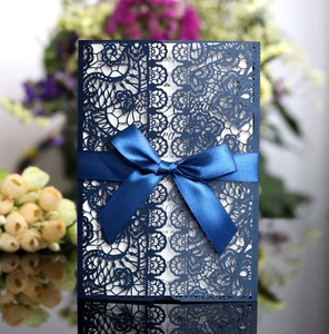 Detail of navy blue laser cut wedding invitation cover with elegant ribbon and white insert
