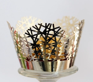 Detail of laser-cut gold snowflake cupcake wrapper with metallic finish for party decor