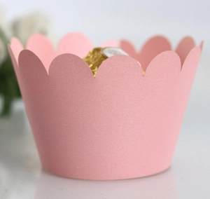 Macro shot of elegant pink scalloped cupcake wrapper with a golden chocolate ball